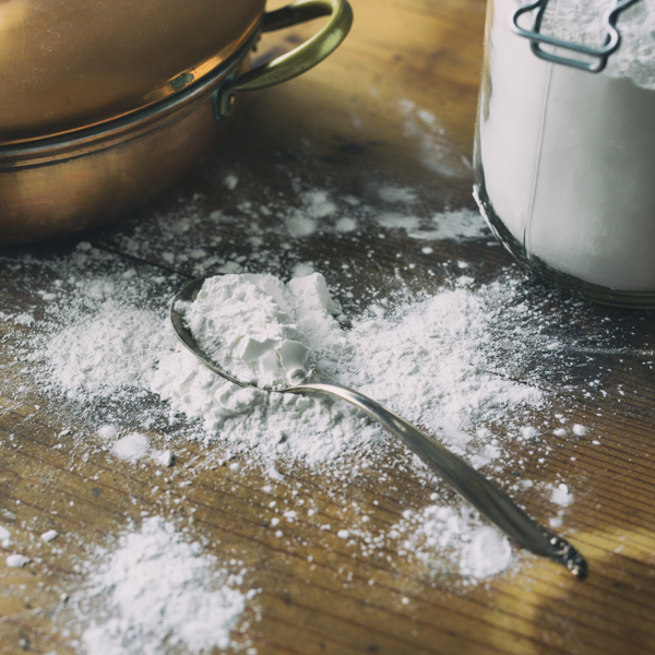 Arrowroot powder
                            spilled on an old wood table. Shown with antique
                            silver spoon and large jar by Aimee Lee_ Alamy Stock
                            Photo
